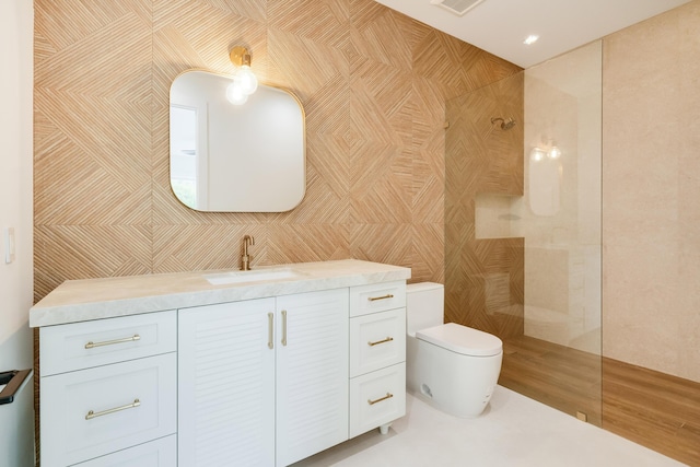 bathroom featuring vanity, toilet, tile walls, and a tile shower