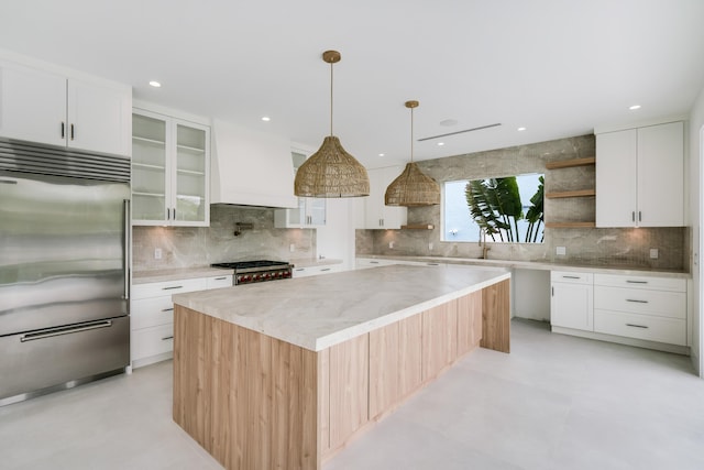 kitchen with stainless steel built in refrigerator, a center island, custom range hood, and white cabinets