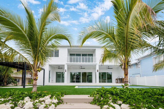 back of house with a balcony, a yard, and ceiling fan