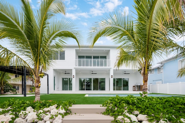 rear view of property with a pool, a balcony, ceiling fan, and a lawn