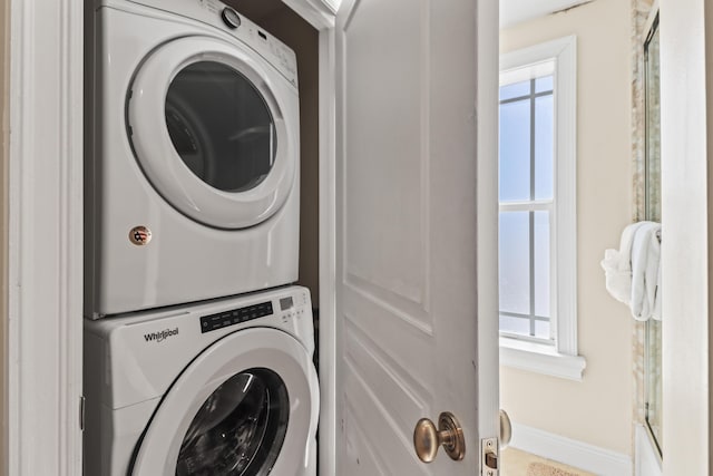 laundry area featuring baseboards, stacked washer / drying machine, and laundry area
