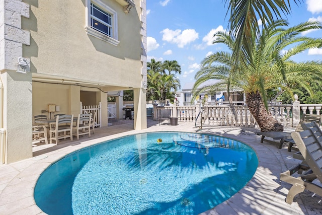 pool featuring fence, a patio, and a grill