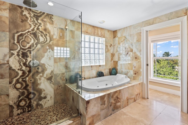 full bathroom with a tile shower, a jetted tub, plenty of natural light, and tile walls