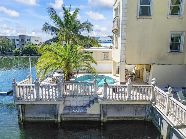dock area with an outdoor pool and a water view
