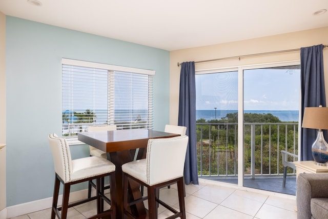 tiled dining room featuring plenty of natural light and a water view