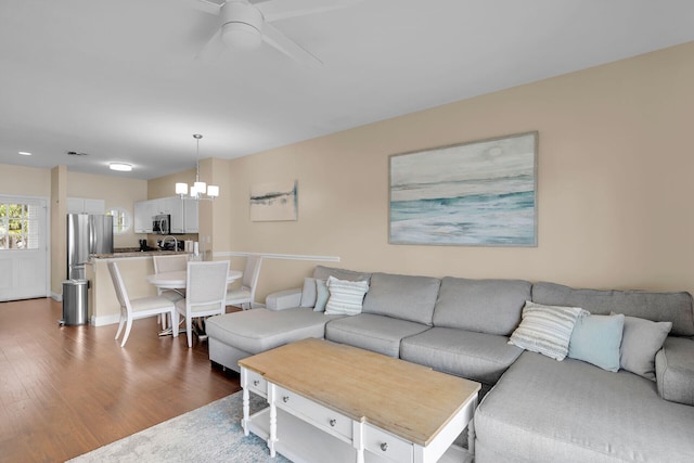 living room featuring dark hardwood / wood-style flooring and ceiling fan with notable chandelier