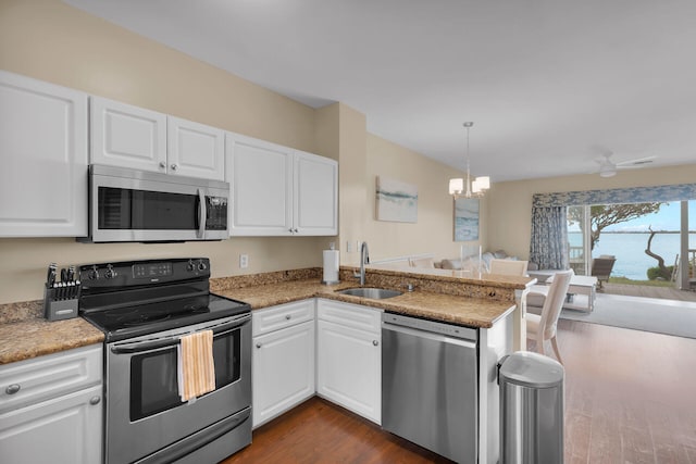 kitchen with decorative light fixtures, white cabinetry, sink, kitchen peninsula, and stainless steel appliances