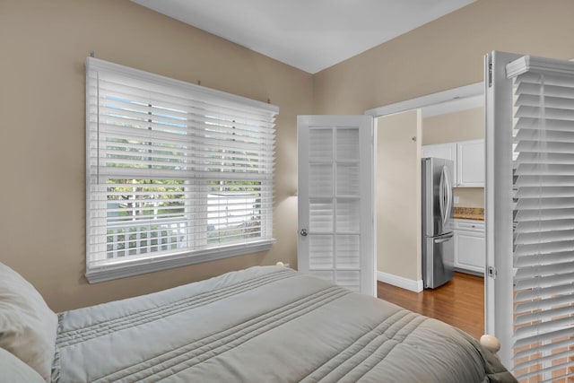 bedroom featuring wood-type flooring and stainless steel refrigerator