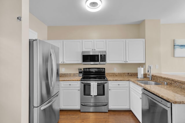 kitchen with white cabinetry, stainless steel appliances, sink, and hardwood / wood-style floors