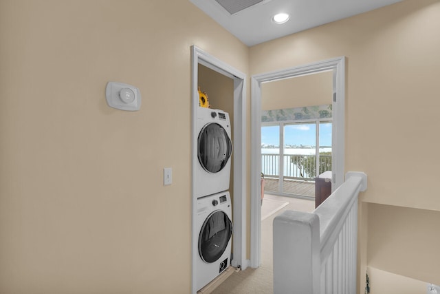 laundry room featuring stacked washer / dryer and light carpet