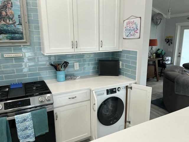 kitchen with gas range, ornamental molding, washer / clothes dryer, decorative backsplash, and white cabinets