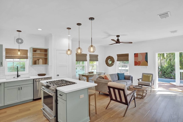 kitchen with visible vents, stainless steel appliances, a sink, light countertops, and backsplash