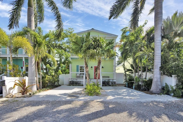 view of front of home with covered porch, driveway, and fence