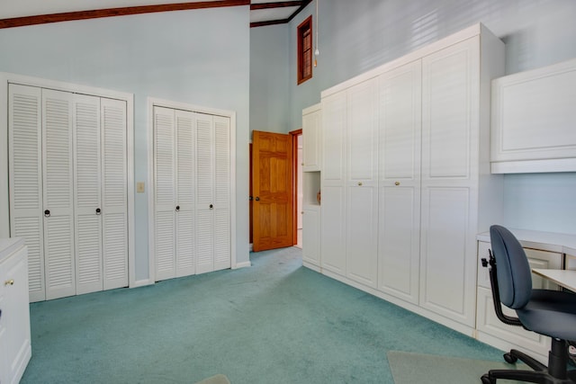 office area featuring light carpet, a high ceiling, and baseboards