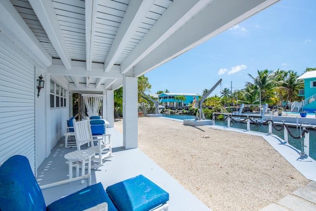 view of patio with a water view and a dock