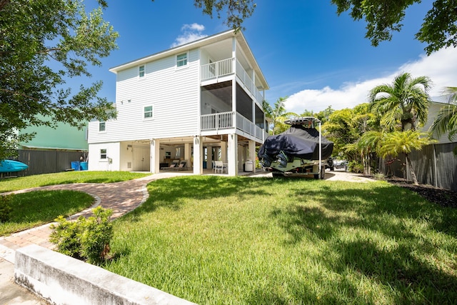 back of house featuring a balcony, a patio, a sunroom, and a lawn