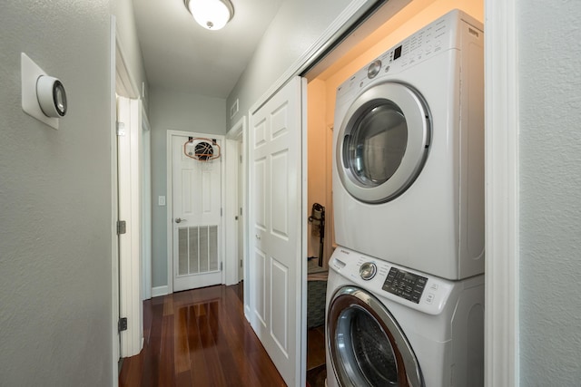 laundry room with stacked washing maching and dryer and dark hardwood / wood-style flooring