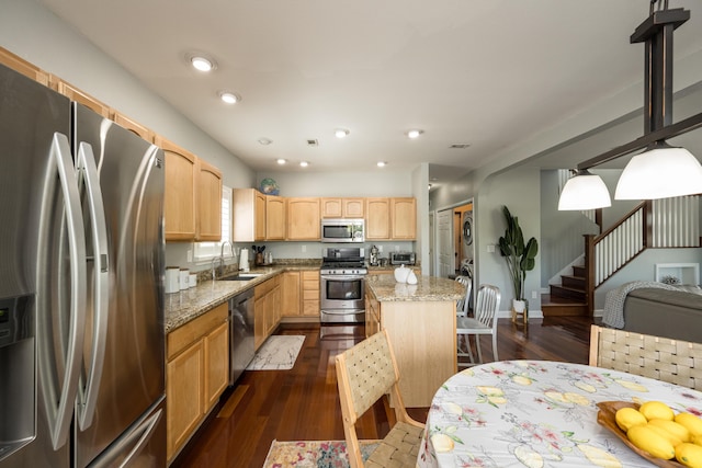 kitchen featuring sink, appliances with stainless steel finishes, a center island, light stone counters, and light brown cabinets