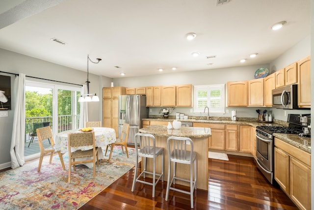 kitchen featuring appliances with stainless steel finishes, pendant lighting, sink, a center island, and light stone countertops