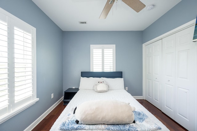 bedroom with dark wood-type flooring, ceiling fan, and a closet