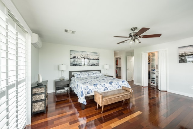 bedroom featuring dark hardwood / wood-style floors, a wall mounted air conditioner, and ceiling fan