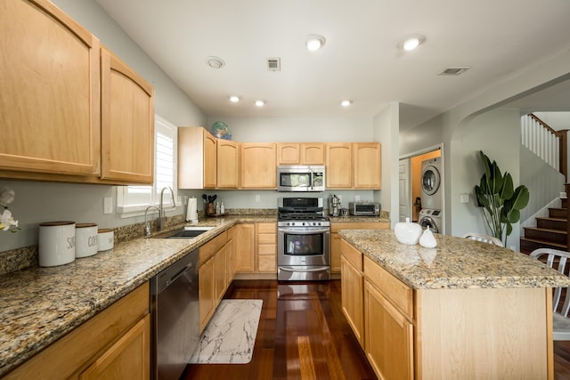 kitchen with stainless steel appliances, stacked washer and clothes dryer, and light brown cabinets