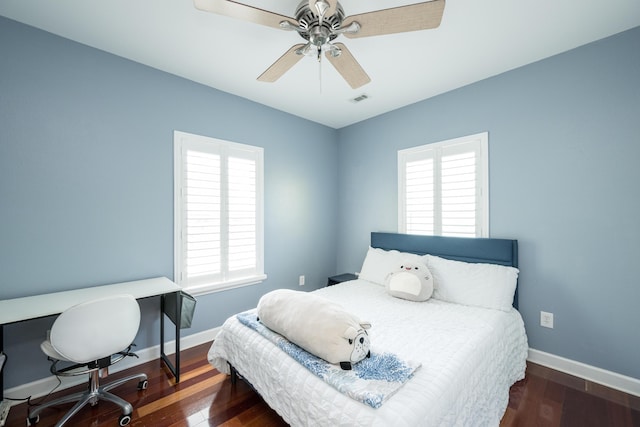 bedroom featuring ceiling fan, dark hardwood / wood-style flooring, and multiple windows