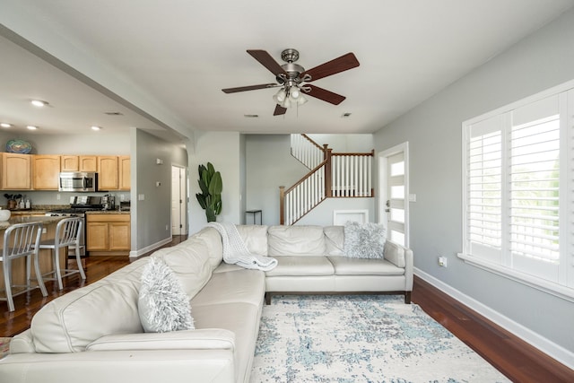 living room featuring dark wood-type flooring and ceiling fan