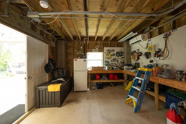 garage featuring a workshop area, a wall mounted AC, and white refrigerator