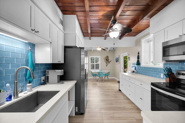 kitchen with sink, stainless steel appliances, tasteful backsplash, white cabinets, and beamed ceiling