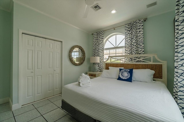 bedroom with crown molding, light tile patterned flooring, ceiling fan, and a closet