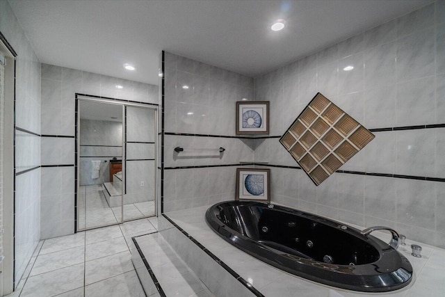 bathroom featuring a relaxing tiled tub, tile patterned floors, and tile walls