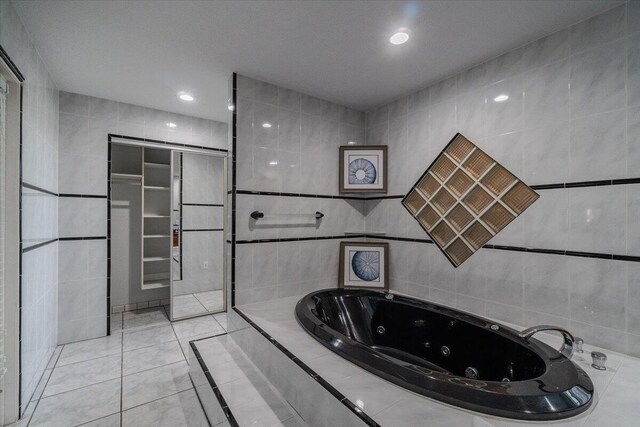 bathroom with tile patterned flooring, tile walls, and tiled tub