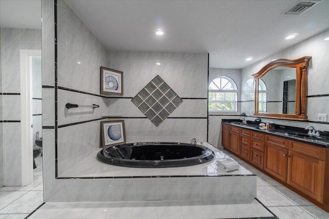 bathroom featuring toilet, tile walls, vanity, tiled bath, and tile patterned flooring