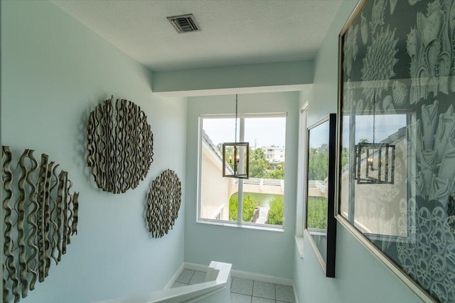 interior space with a chandelier, tile patterned flooring, and a textured ceiling