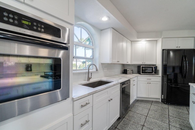 kitchen with white cabinetry, sink, tasteful backsplash, and black appliances