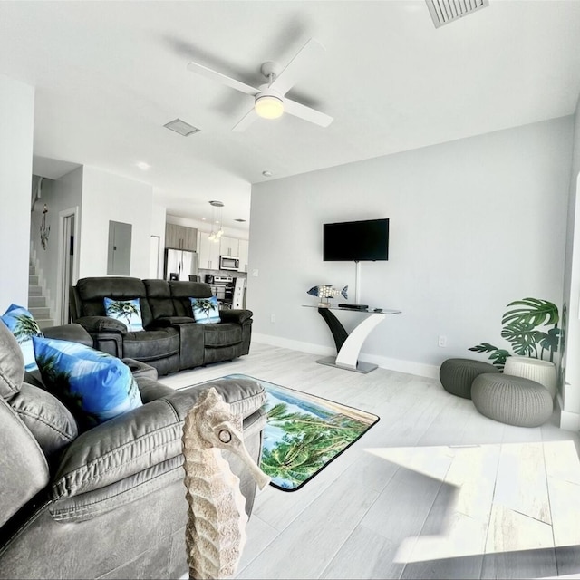 living room featuring electric panel, light hardwood / wood-style floors, and ceiling fan