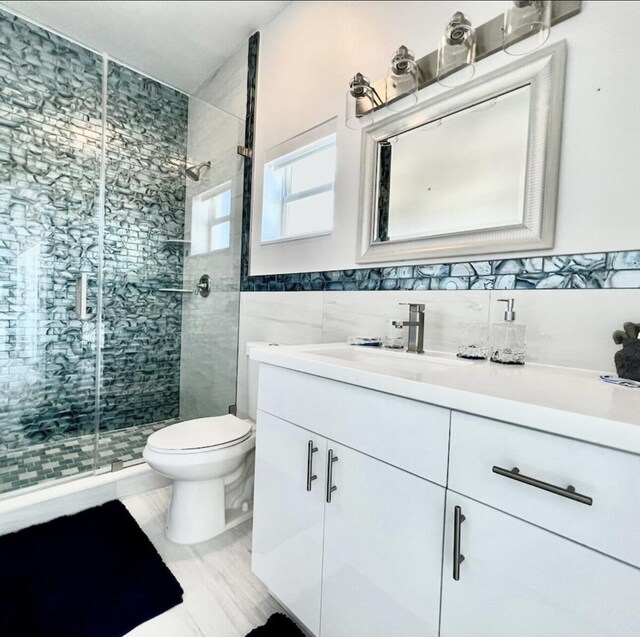 bathroom featuring tile walls, vanity, a shower with door, and toilet