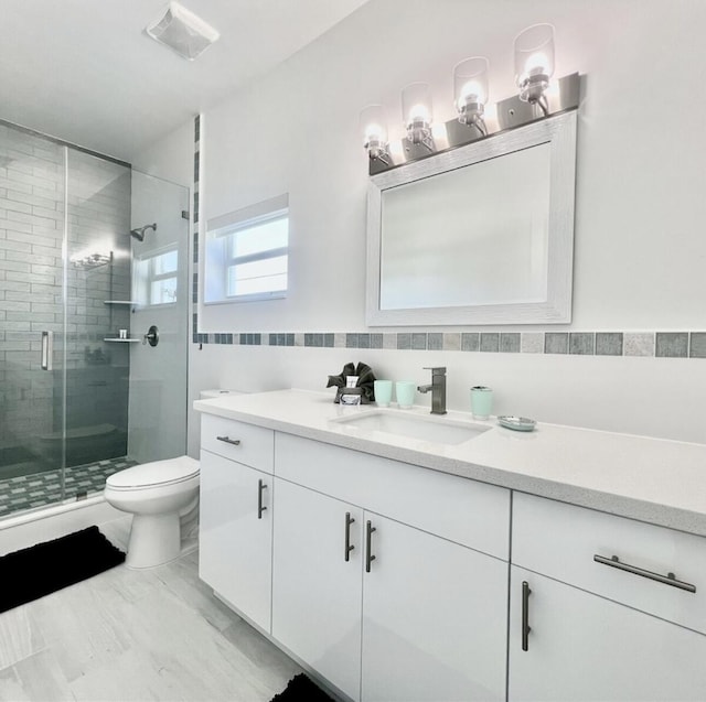 bathroom featuring vanity, a shower with shower door, tile walls, and toilet