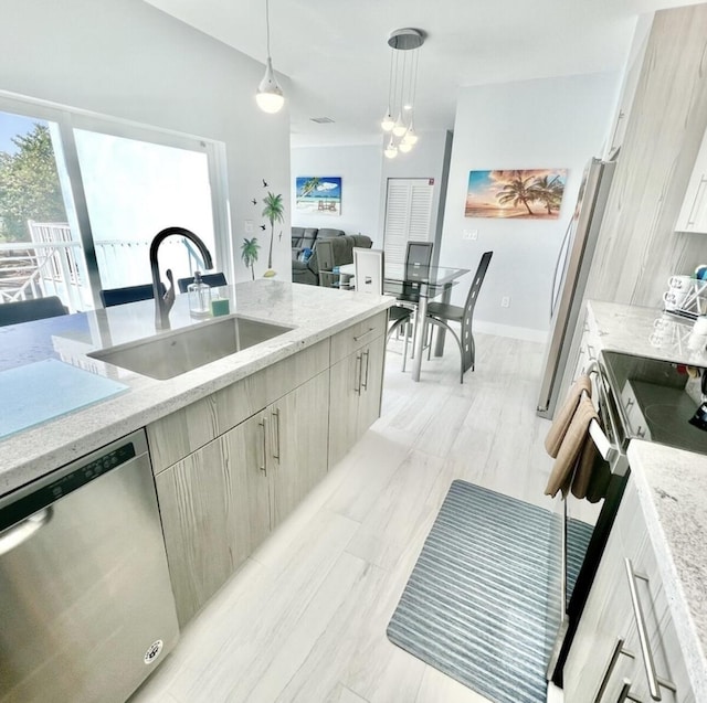 kitchen with sink, decorative light fixtures, stainless steel appliances, and light stone countertops