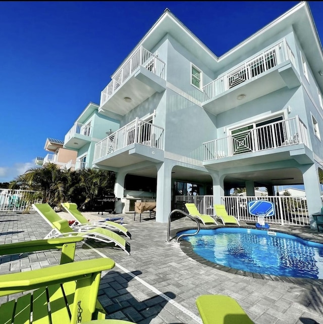 rear view of property featuring a fenced in pool and a patio area