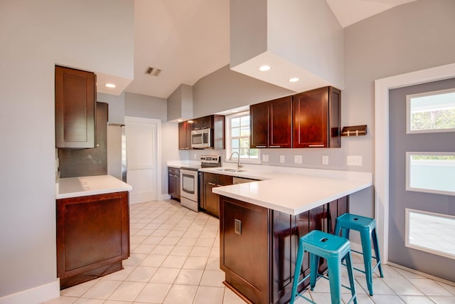 kitchen featuring light tile patterned flooring, a breakfast bar, sink, appliances with stainless steel finishes, and kitchen peninsula