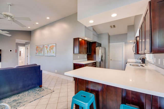 kitchen with lofted ceiling, sink, appliances with stainless steel finishes, kitchen peninsula, and ceiling fan