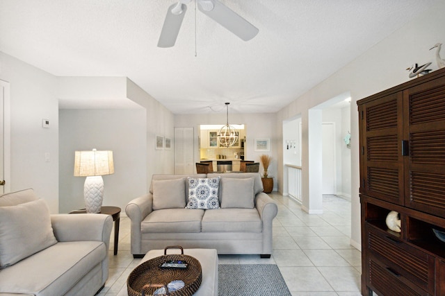 tiled living room featuring ceiling fan with notable chandelier and a textured ceiling