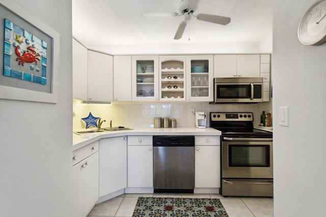 kitchen featuring stainless steel appliances, tasteful backsplash, light tile patterned floors, and white cabinets