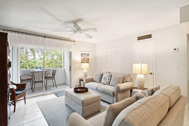 living room featuring light tile patterned flooring, ceiling fan, and a textured ceiling