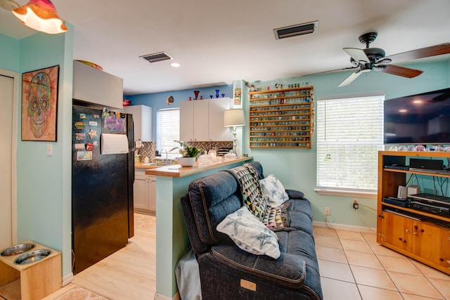 kitchen featuring visible vents, tasteful backsplash, freestanding refrigerator, and white cabinetry