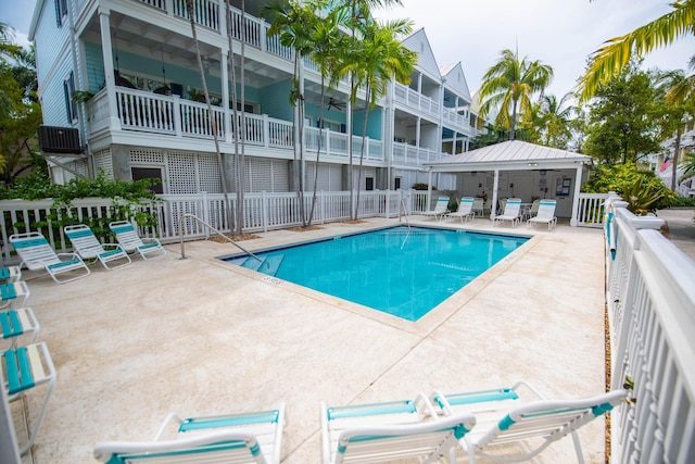 pool with a ceiling fan, fence, and a patio