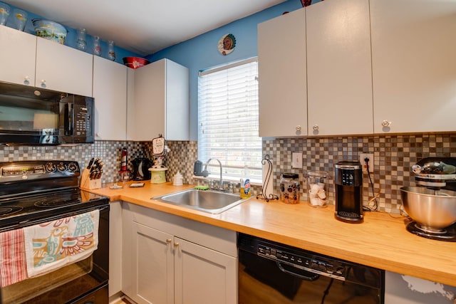 kitchen featuring tasteful backsplash, white cabinets, a sink, and black appliances