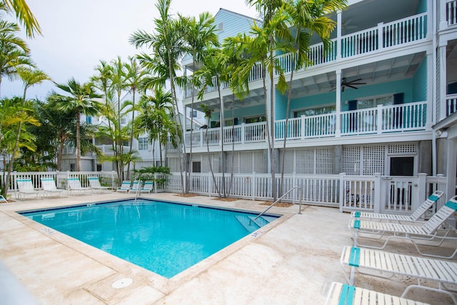 community pool with a patio area, ceiling fan, and fence